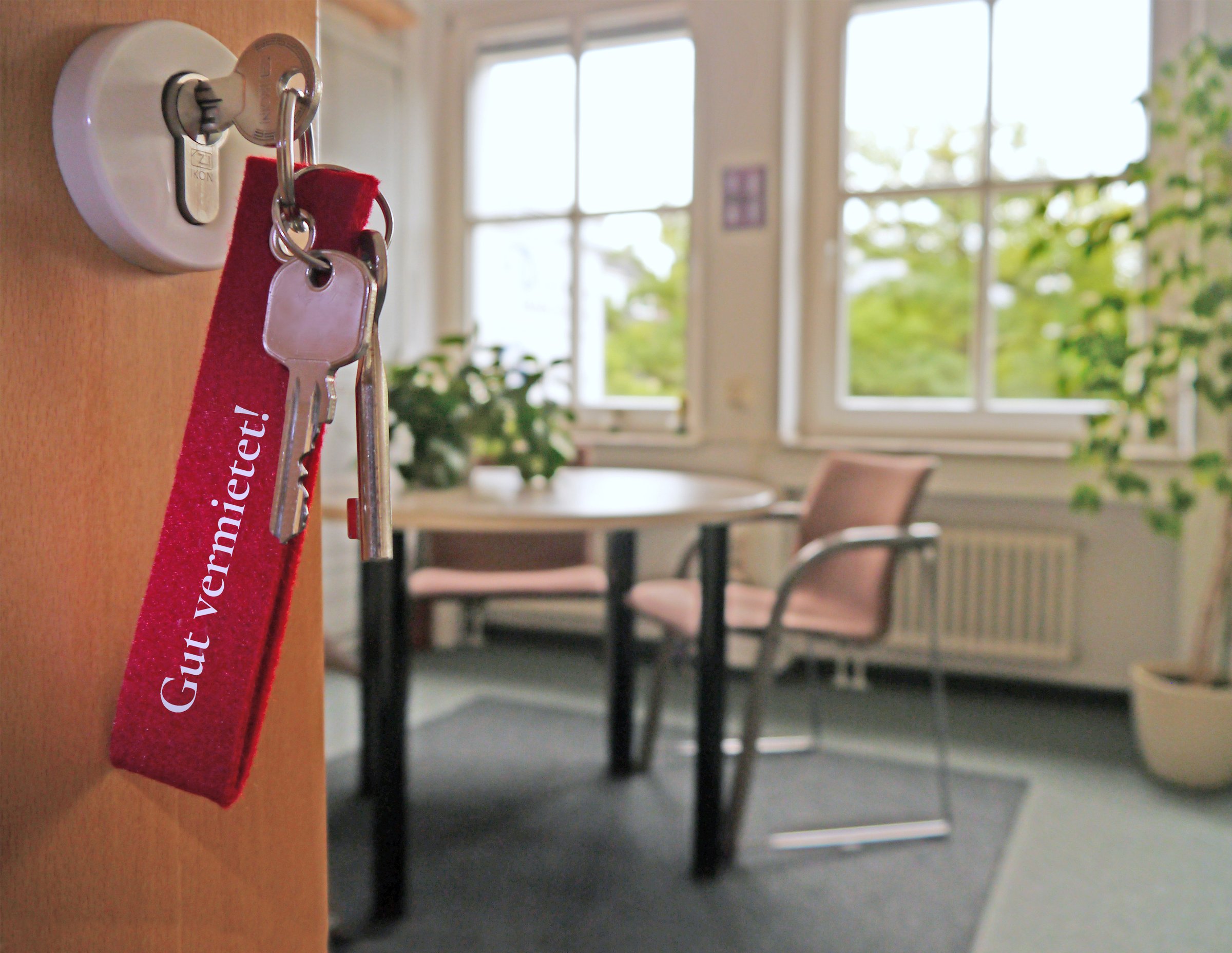 Schlüssel mit Anhänger „Gut vermietet!“ in einer Wohnungstür